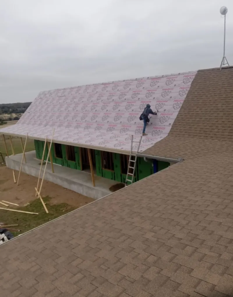 Worker preparing underlayment for a metal roof installation in Chili